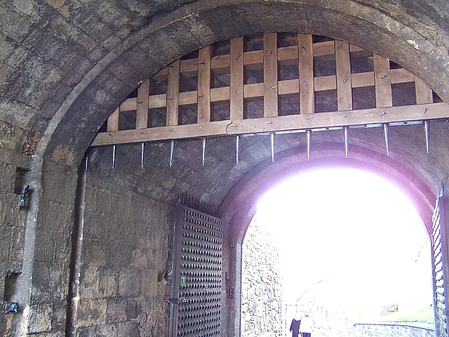 Inside the Portcullis Gate: the raised wooden portcullis above a stone archway, with daylight beyond the passage